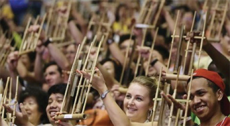 Picture of a big group of people each one holding up the Anglung instrument which is made of bamboo.