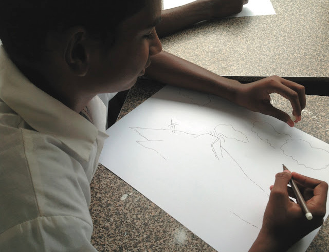 A student draws a volcano; nature and the environment feature prominently in the students’ work.