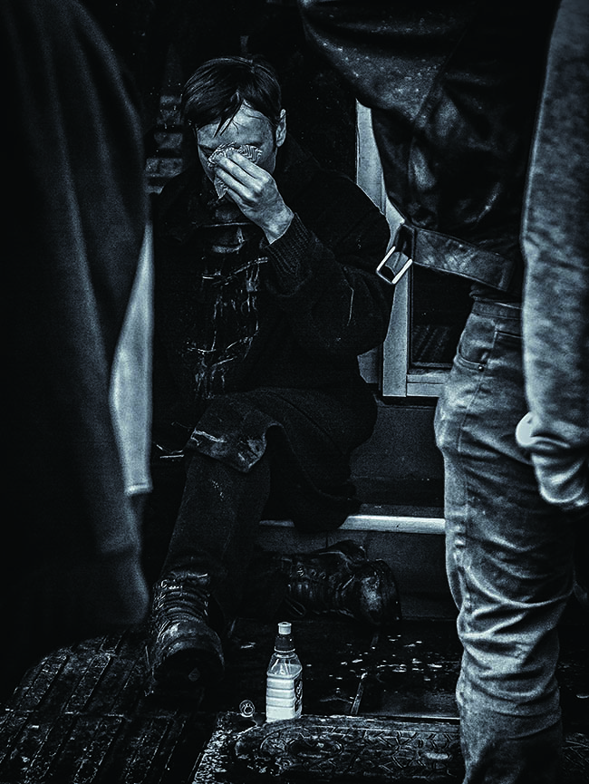 Black and white image of sitting man holding cloth to eyes.